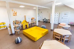 Sala żłobka z żółtymi materacami, domkiem i zabawkami dla dzieci