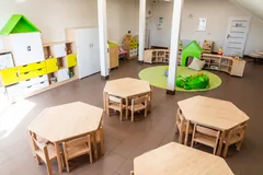 Drewniane stoliki i krzesełka oraz zielony kącik zabaw w Toy House